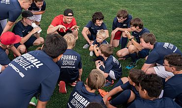 Trainer und Teilnehmende der RB Fußballschule bei einer Teambesprechung