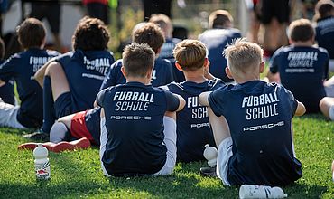 Teilnehmende der RB Fußballschule sitzen auf dem Fußballplatz