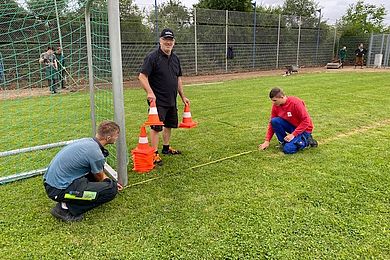 3 Männer auf einem Fußballplatz