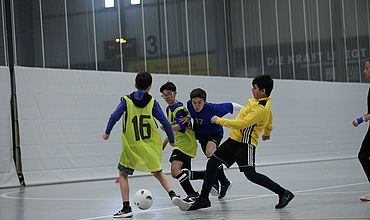 Einige Kinder rennen um den Fußball und versuchen, ihn an sich zu nehmen